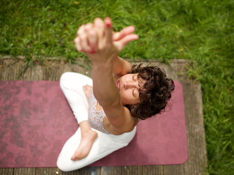 Vista desde arriba de una chica haciendo yoga en el campo.