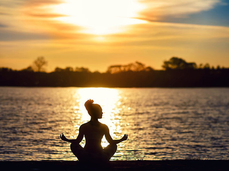 Una chica meditando al atardecer en un lago